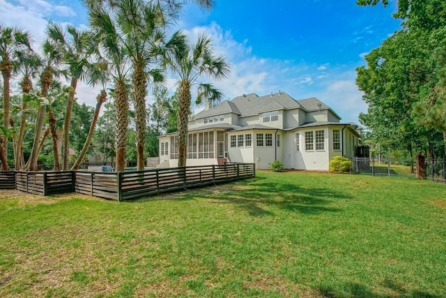 back of house featuring a lawn, fence, and a sunroom