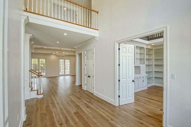 hall featuring recessed lighting, baseboards, light wood-style flooring, and a towering ceiling