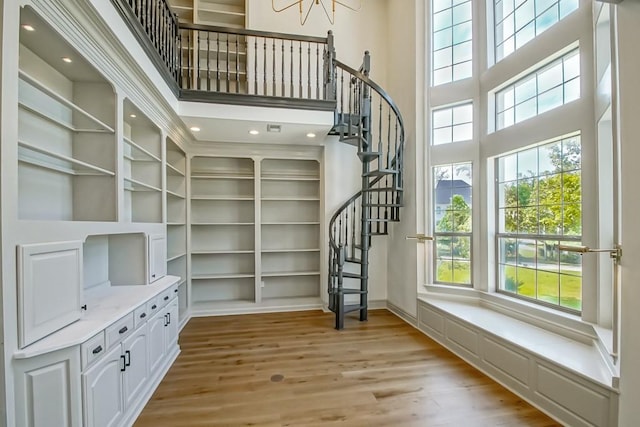 sitting room with light wood finished floors, stairway, a high ceiling, and baseboards