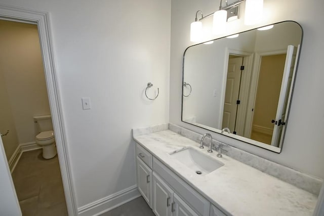 bathroom featuring toilet, vanity, and baseboards