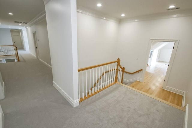 hallway with an upstairs landing, visible vents, recessed lighting, and crown molding