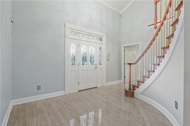 entrance foyer featuring baseboards, stairs, a towering ceiling, and crown molding