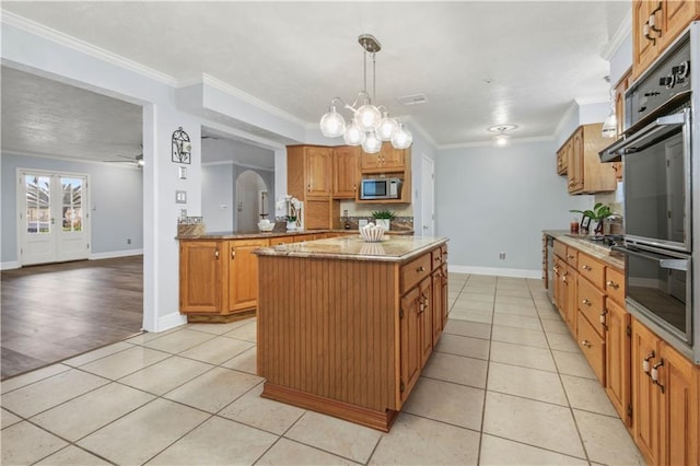 kitchen with pendant lighting, stainless steel microwave, ornamental molding, light tile patterned flooring, and a kitchen island