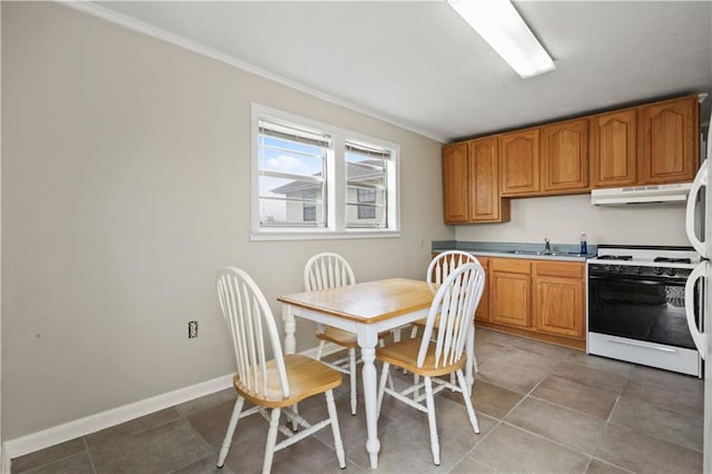 kitchen featuring baseboards, brown cabinets, light countertops, white gas stove, and under cabinet range hood