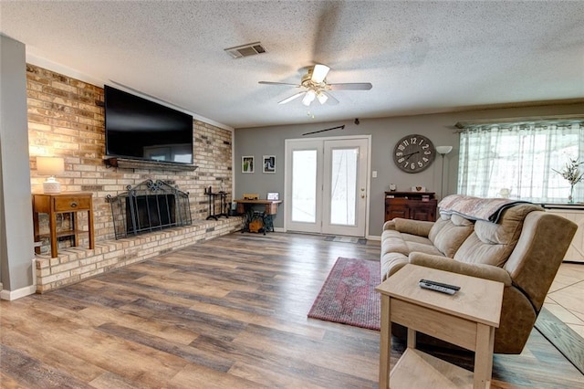 living room with a wealth of natural light, a brick fireplace, and wood finished floors