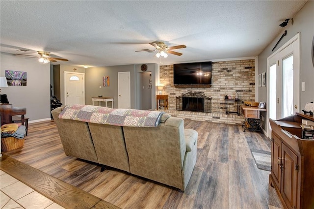 living area with a brick fireplace, a textured ceiling, and wood finished floors