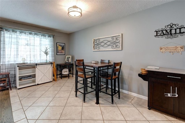 dining room featuring a textured ceiling, baseboards, and light tile patterned floors