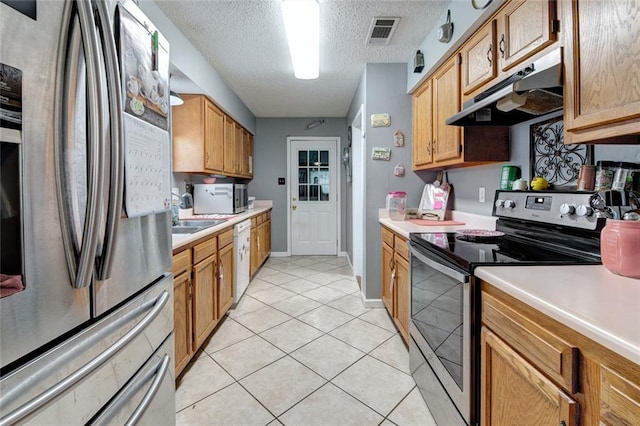 kitchen with stainless steel appliances, light countertops, visible vents, light tile patterned flooring, and under cabinet range hood