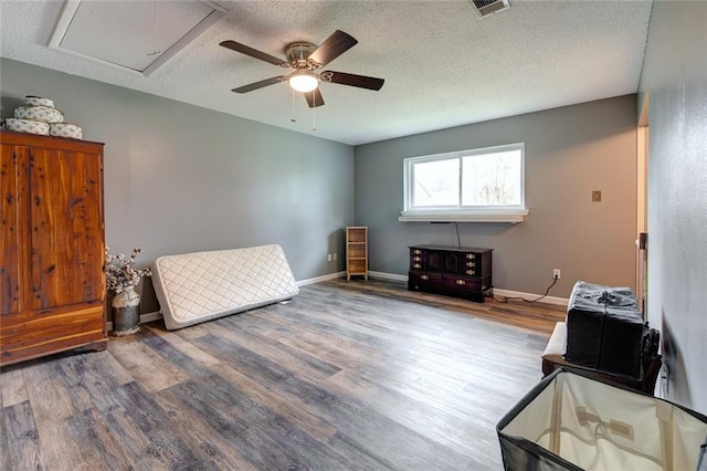 sitting room featuring attic access, a textured ceiling, baseboards, and wood finished floors