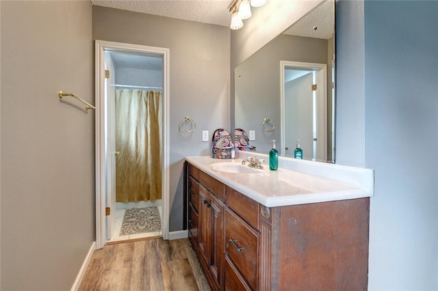 full bathroom featuring a textured ceiling, wood finished floors, vanity, baseboards, and a shower with curtain