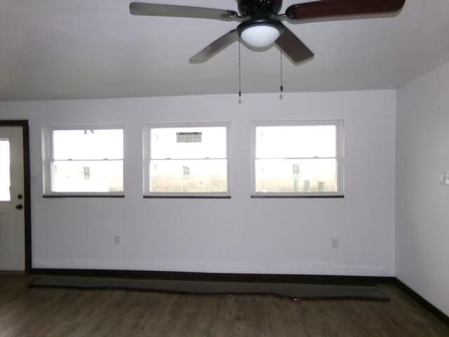 empty room featuring a ceiling fan, baseboards, and wood finished floors