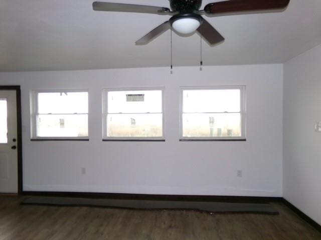 empty room featuring ceiling fan, baseboards, and wood finished floors