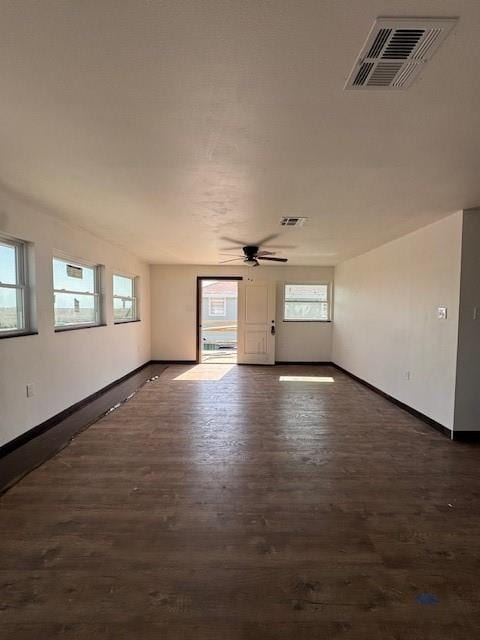 unfurnished room featuring visible vents, baseboards, ceiling fan, and dark wood-style flooring