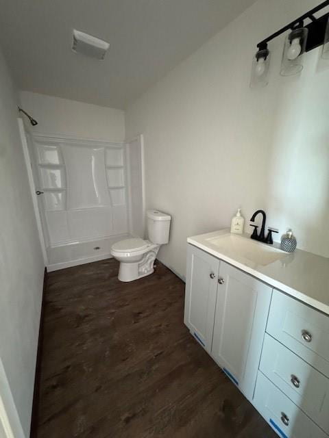 bathroom featuring vanity, toilet, a shower, and wood finished floors