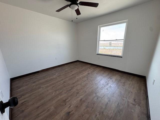 spare room with baseboards, ceiling fan, and wood finished floors