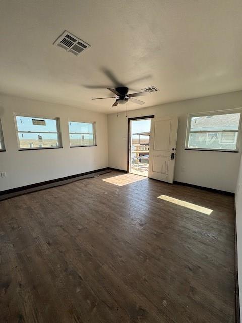unfurnished room with dark wood finished floors, baseboards, visible vents, and ceiling fan