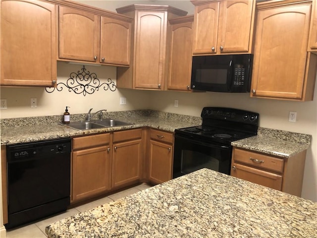 kitchen featuring black appliances, light stone counters, and a sink