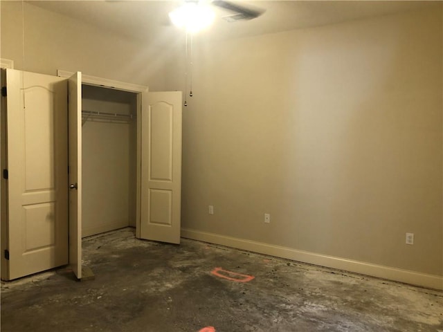 unfurnished bedroom featuring concrete flooring, a closet, and baseboards