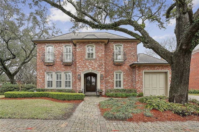 view of front of home featuring a garage, brick siding, and roof with shingles