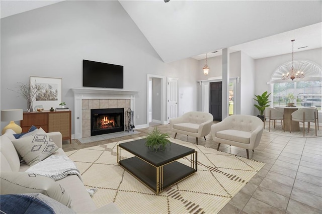 living area featuring a notable chandelier, light tile patterned floors, high vaulted ceiling, a tile fireplace, and baseboards