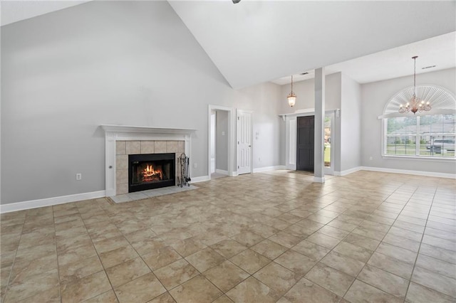 unfurnished living room with a notable chandelier, high vaulted ceiling, a tile fireplace, baseboards, and tile patterned floors