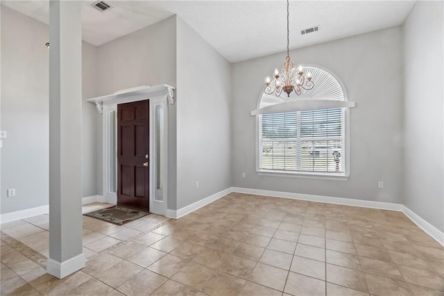 foyer with an inviting chandelier, baseboards, light tile patterned floors, and visible vents