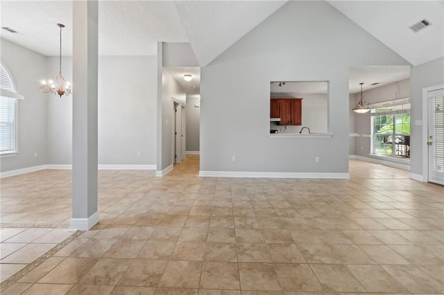 unfurnished living room with light tile patterned floors, baseboards, visible vents, an inviting chandelier, and high vaulted ceiling