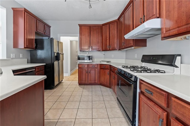 kitchen featuring under cabinet range hood, gas range oven, light countertops, black refrigerator with ice dispenser, and stainless steel microwave