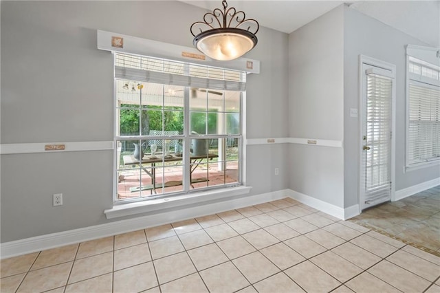 empty room with baseboards and light tile patterned floors