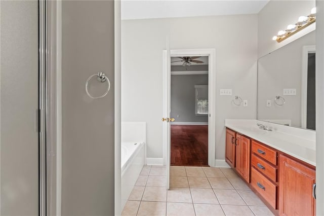 bathroom featuring ceiling fan, a garden tub, vanity, baseboards, and tile patterned floors