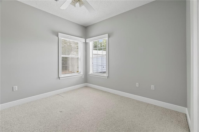 empty room with light carpet, a ceiling fan, baseboards, and a textured ceiling