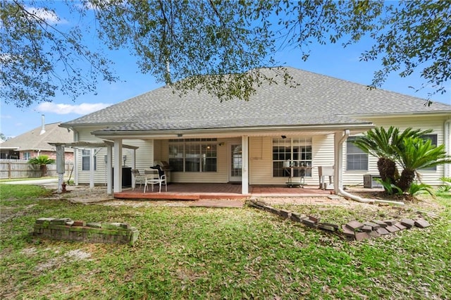 rear view of property featuring fence, a lawn, and roof with shingles