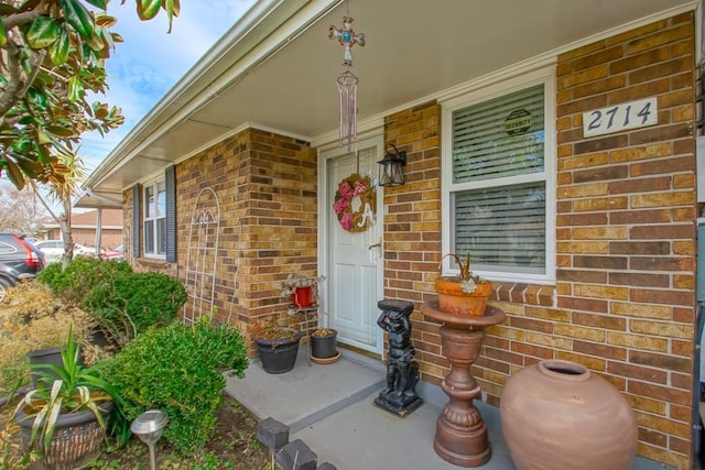 view of exterior entry featuring covered porch and brick siding