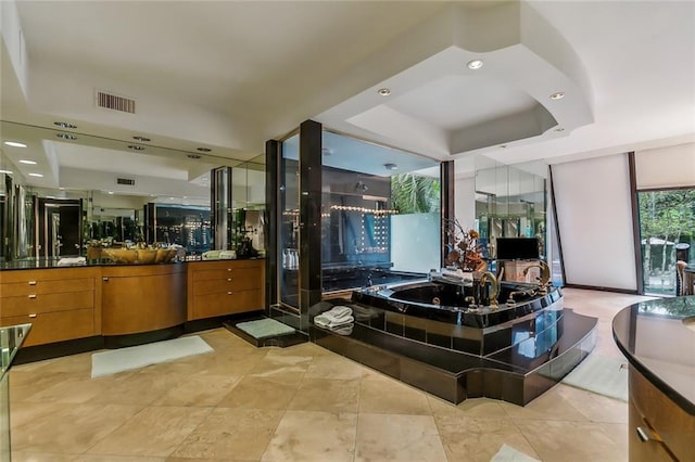 full bath with a whirlpool tub, visible vents, a raised ceiling, and vanity