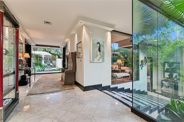 foyer with marble finish floor, visible vents, and floor to ceiling windows