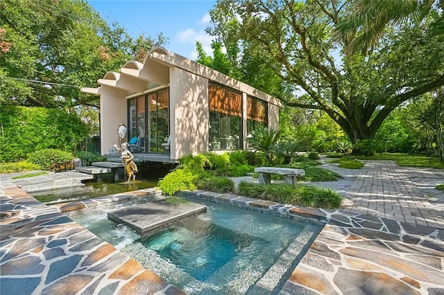 back of house featuring an in ground hot tub and a patio area