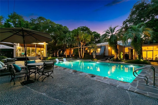 pool at dusk featuring a patio area and an outdoor pool