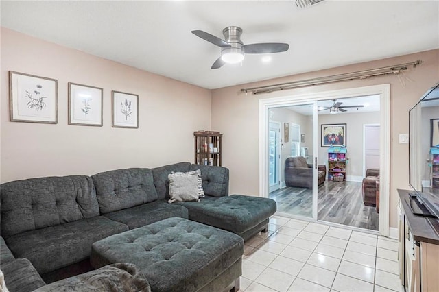 living area featuring light tile patterned floors, a ceiling fan, and baseboards