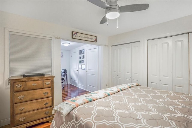 bedroom with multiple closets, dark wood finished floors, baseboards, and a ceiling fan