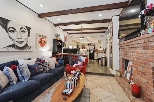 living room featuring a ceiling fan, a brick fireplace, light tile patterned flooring, and beamed ceiling