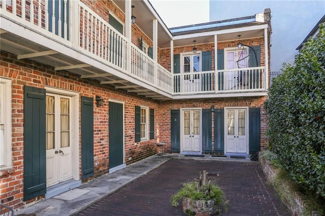 back of property featuring brick siding and a balcony