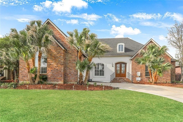 view of front of property with french doors, concrete driveway, a front lawn, and stucco siding