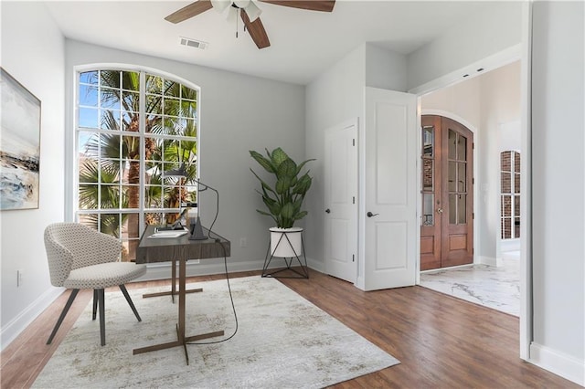 office space featuring visible vents, wood finished floors, arched walkways, baseboards, and ceiling fan