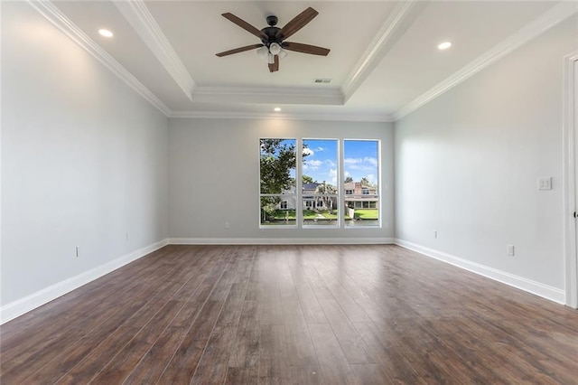 empty room featuring a tray ceiling, baseboards, ornamental molding, and dark wood-style flooring