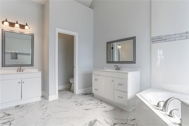 bathroom featuring toilet, two vanities, baseboards, and marble finish floor