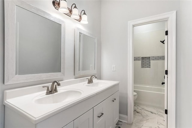 bathroom with double vanity, marble finish floor, toilet, and a sink