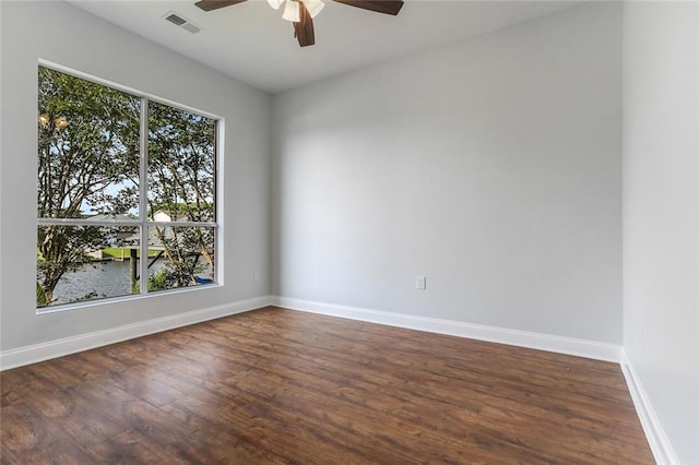 empty room featuring a wealth of natural light, baseboards, a ceiling fan, and dark wood-style flooring