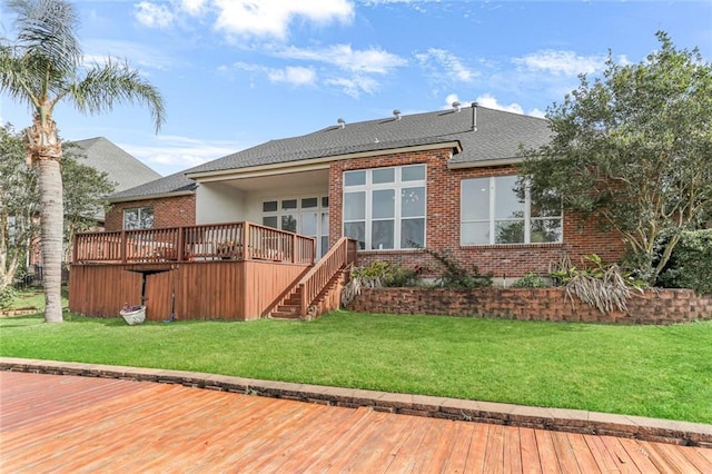 back of property with a deck, a lawn, and brick siding