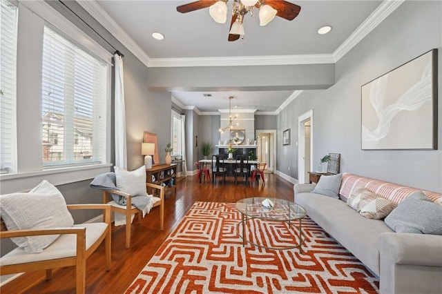 living area with baseboards, ceiling fan, wood finished floors, and crown molding