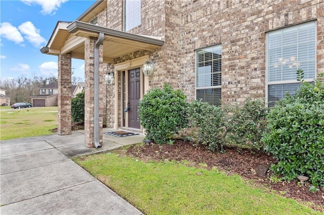 property entrance with a yard and brick siding